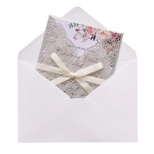 Detail view of silver glitter lace invitation with a white silk bow and floral accents