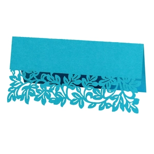 Macro view of blue laser-cut place card with detailed hollow leaf and floral patterns