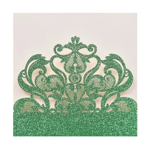 Close-up of dark green glitter laser-cut lace invitation with intricate baroque pattern