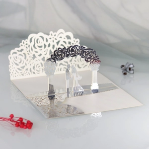 Macro view of 3D laser-cut wedding invitation featuring rose arch and kissing couple