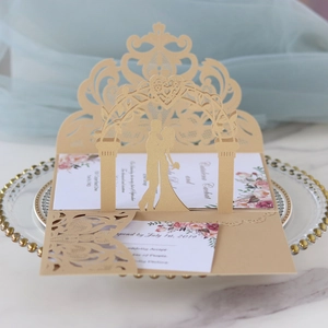 Detail of laser-cut 3D gold wedding invitation with floral arch and couple silhouette