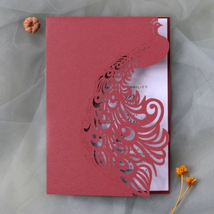 Close-up of red laser-cut peacock wedding invitation with elegant pearlescent finish