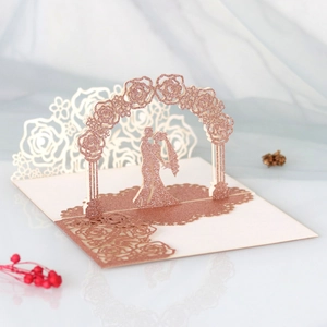 3D laser-cut wedding card featuring a glittery rose arch and kissing couple silhouette