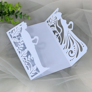 Intricate laser-cut white wedding invitation featuring a romantic bride and groom silhouette
