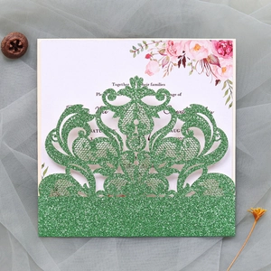 Close-up of laser-cut green glitter wedding invitation with elegant floral insert card