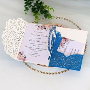 Detailed laser-cut rose wedding invitation with glitter finish on a decorative glass tray