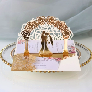 Macro view of 3D laser cut wedding invitation with golden rose arch and couple silhouette