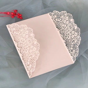 Détail de l'invitation de mariage rose clair découpée au laser avec dentelle florale
