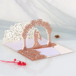 3D laser-cut wedding invitation featuring a rose gold glitter arch and couple silhouette