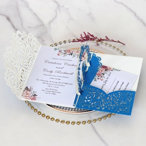 Détail de l'invitation de mariage rose découpée au laser avec paillettes bleues et fleurs