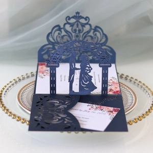 Detail of laser-cut navy blue wedding invitation with floral insert on a decorative plate