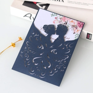 Detail of laser-cut navy blue wedding invitation with silhouette and floral inner card