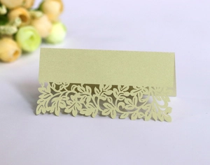 Macro detail of laser-cut leaf pattern on light green pearlescent paper wedding table card