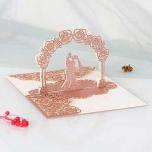 Detail of 3D laser-cut rose gold wedding card with silhouette of a couple kissing