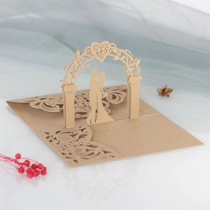 Close-up of 3D laser-cut wedding invitation featuring champagne gold lace and couple motif