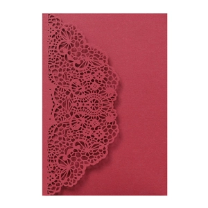 Macro detail of wine red laser-cut lace pattern on heavy specialty paper invitation