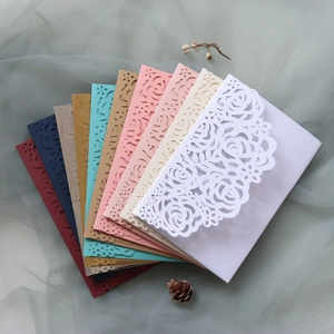 Dettaglio di motivi a rose tagliati al laser su buste da matrimonio multicolore