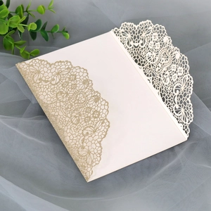Close-up of laser-cut lace wedding invitation with champagne gold glitter finish