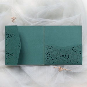 Macro view of laser-cut floral lace pattern on dark green tri-fold invitation cover