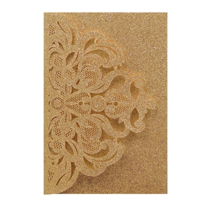 Macro view of laser-cut baroque floral patterns on gold glitter paper wedding invitation