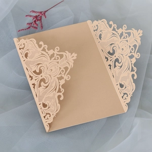 Detail of laser-cut wedding invitation with intricate floral lace and metallic gold finish