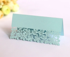 Detail of laser-cut leaf pattern on mint green tent-style wedding place card