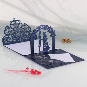 Detail of navy blue laser cut wedding invitation with silhouette under an arch