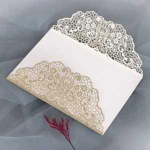 Macro detail of laser-cut lace pattern and gold glitter on wedding invitation