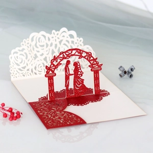 Detail of 3D laser cut wedding card showing red glitter arch and couple silhouette
