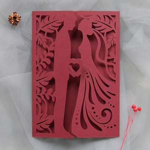 Detailed laser-cut heart and couple silhouette on a deep red wedding invitation card