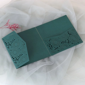Detail of dark green laser-cut wedding invitation cover with floral lace on white gauze