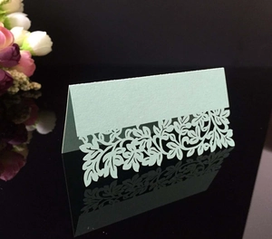 Elegant laser-cut light green wedding place cards with hollow floral pattern and tent fold