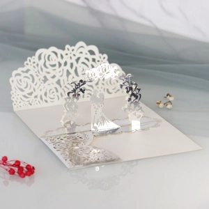 Dettaglio dell'invito di nozze 3D con motivi a rose e silhouette di una coppia