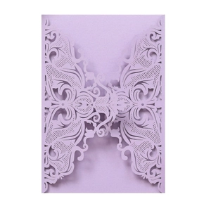 Macro detail of the laser-cut butterfly lace pattern on a purple wedding invitation cover