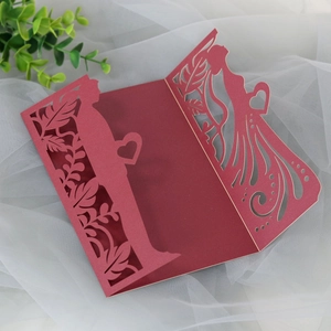 Detailed laser-cut wedding invitation cover in burgundy with delicate silhouette patterns