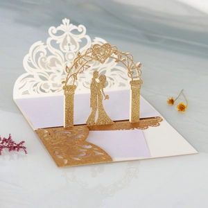 Detail of 3D pop-up wedding card showing a laser-cut gold glitter floral arch and couple