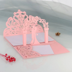 Close-up of 3D laser cut pink wedding card showing detailed gate and couple silhouette