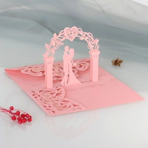 Detail showing pink laser-cut 3D pop-up wedding card with romantic couple and arch