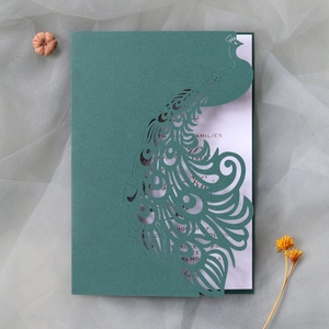 Detailed laser-cut peacock wedding invitation in deep green with elegant gold print