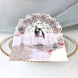 Detailed laser-cut 3D wedding invitation with rose arch and silhouette on decorative tray