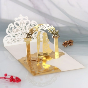 Macro view of 3D laser cut wedding invitation with gold foil floral arch and bride silhouette