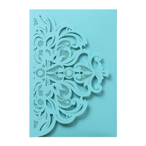 Macro detail of laser-cut European floral lace pattern on light blue wedding invitation