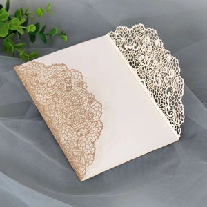 Detailed laser cut lace wedding invitation cover in cream with champagne gold glitter accents