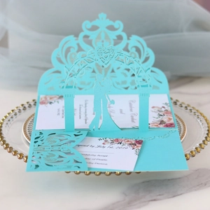 Detailed laser-cut Tiffany blue wedding invitation with elegant lace silhouettes on a glass plate