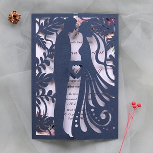 Macro view of laser-cut navy wedding card with bridal silhouette and floral details