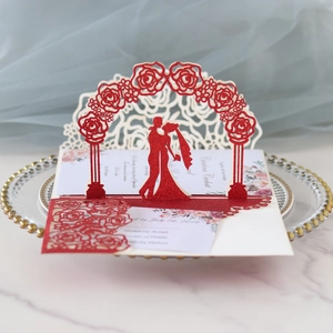 Close-up of 3D laser-cut rose arch wedding invitation with red glitter finish and silhouettes