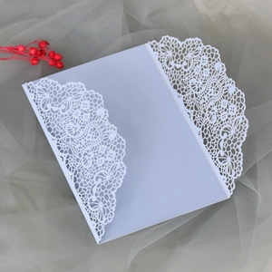 Détail d'invitation de mariage découpée au laser avec motifs de dentelle et papillons bleus