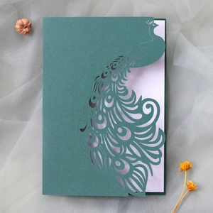 Detail of laser-cut peacock wedding invitation in emerald green with intricate paper art