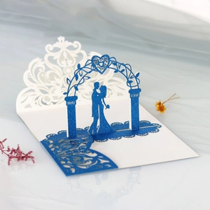 Detail of laser-cut wedding invitation featuring a couple silhouette and glitter finish