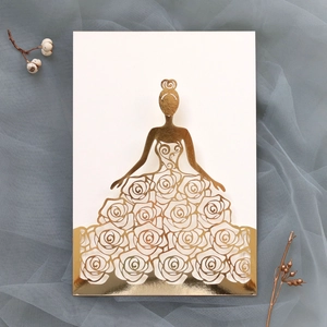Detail of laser-cut wedding invitation featuring a girl in a golden rose dress design